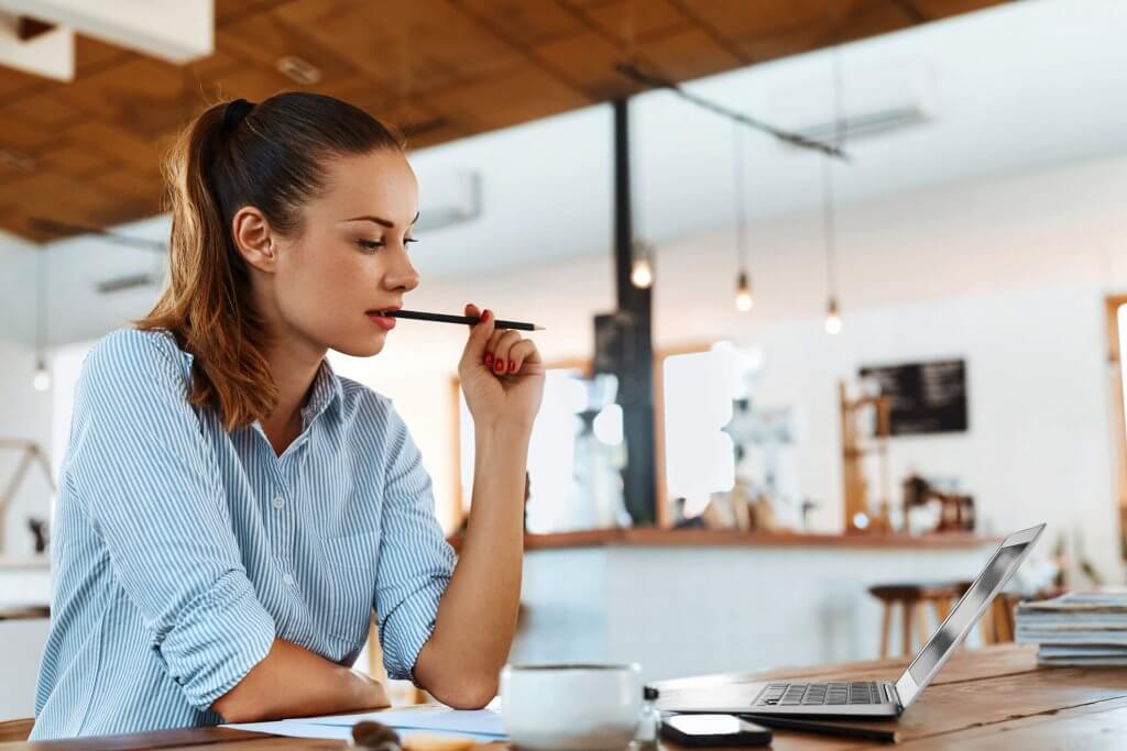 woman working at desk while chewing on pencil