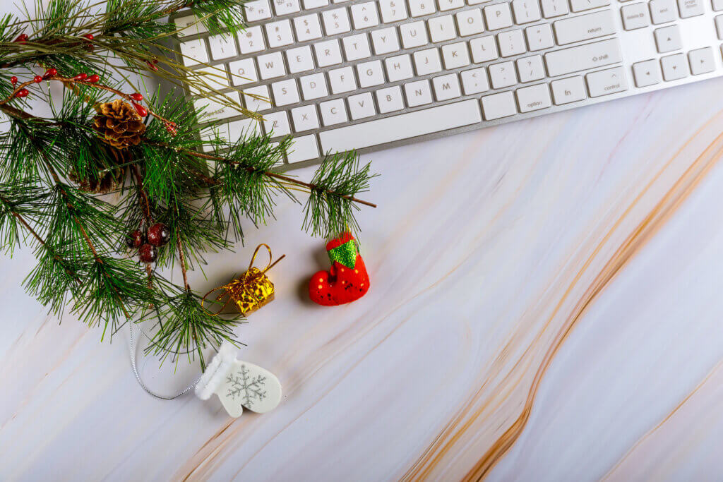Close-up of computer keyboard with ornaments on the Christmas tree