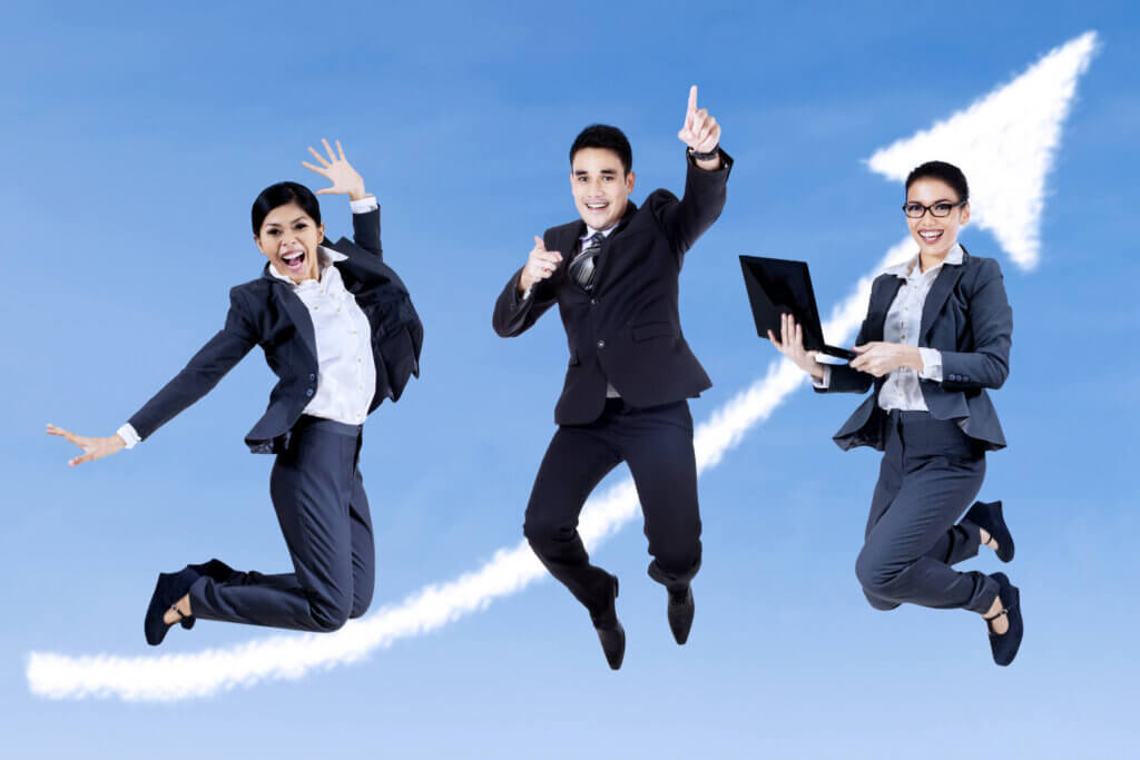 three smiling people in suits jump in mid air