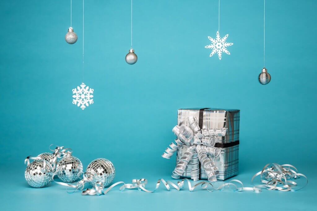 gift boxes wrapped in silver surrounded by silver baubles