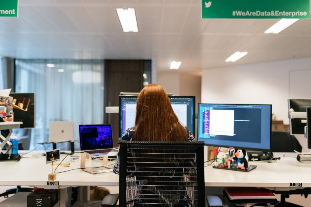 woman working on desk with three computers