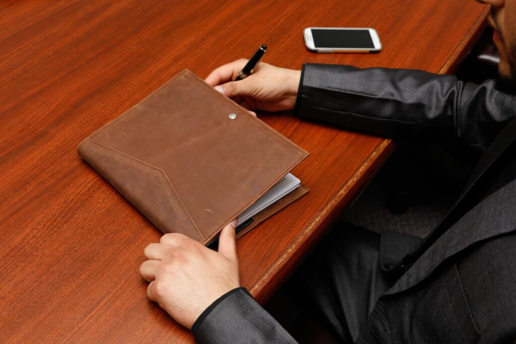 Person Holding Brown Leather Book