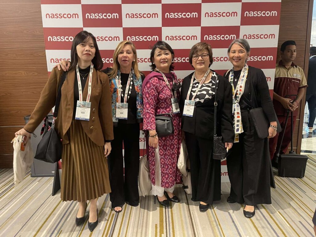 five women posing for a photo in front of the NASSCOM backdrop