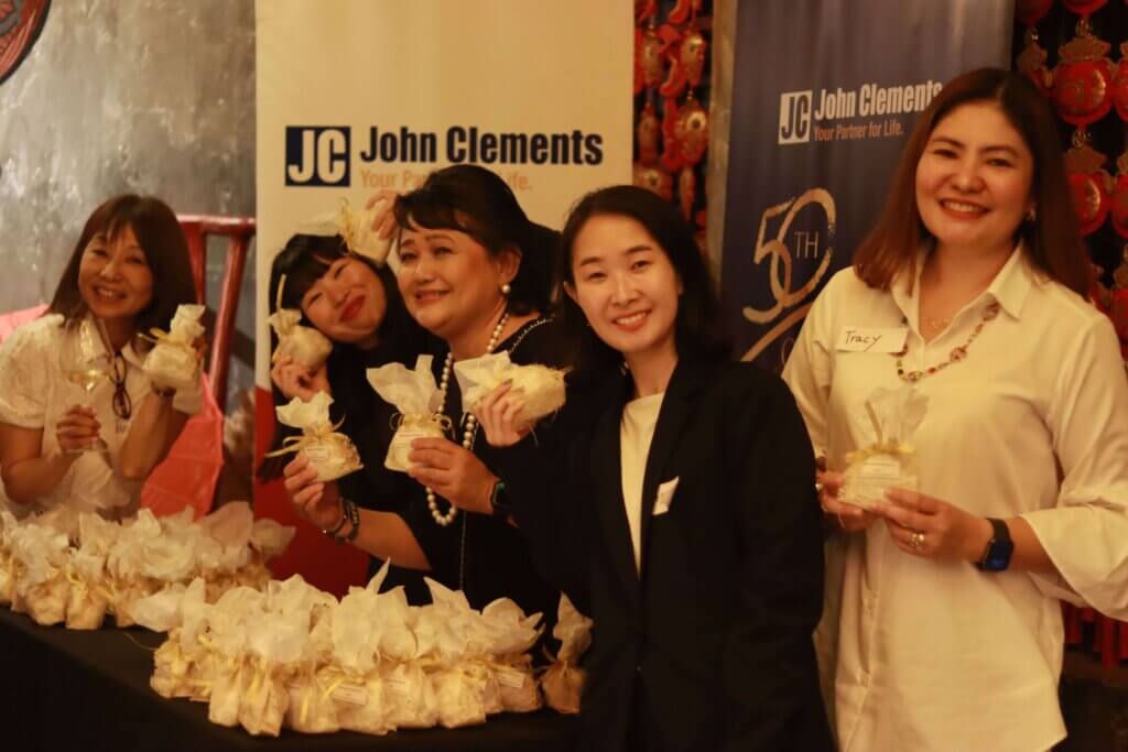 a group of women holding event souvenirs in white bags